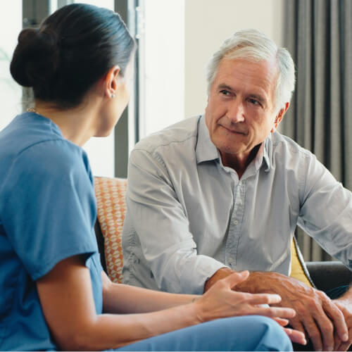 Nurse talking to patient on couch.